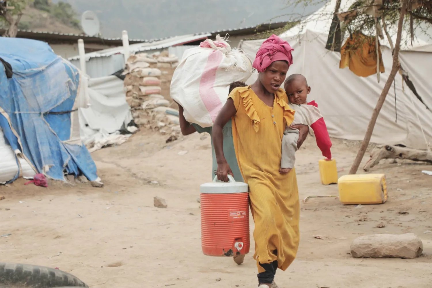 Families collecting water in a displacement site &mdash; the daily reality this response is built around.
